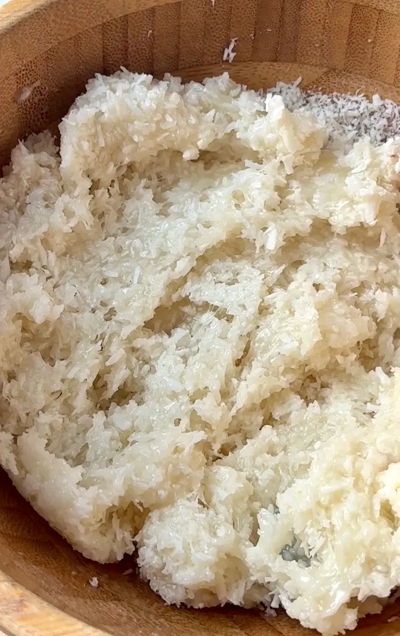 Desiccated coconut mixed into the condensed coconut milk and coconut butter in a wooden bowl