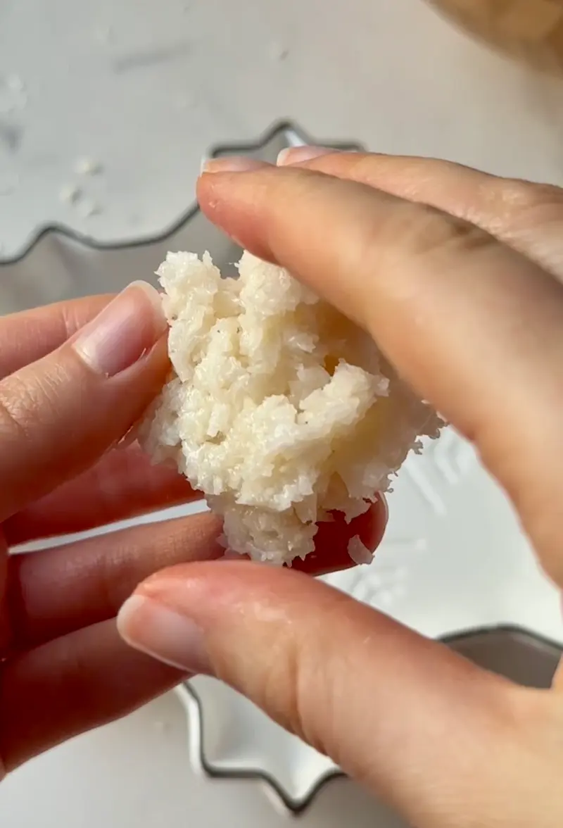 Hands rolling the coconut truffle mixture into a smooth ball