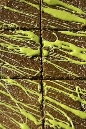 Easy healthy matcha cake cut into squares seen from above with bright green matcha icing drizzled across in diagonal lines