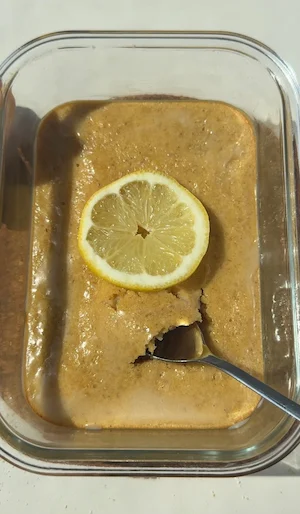 A lemon drizzle pancake bowl with a white monk fruit drizzle on top, served in an oven-safe bowl