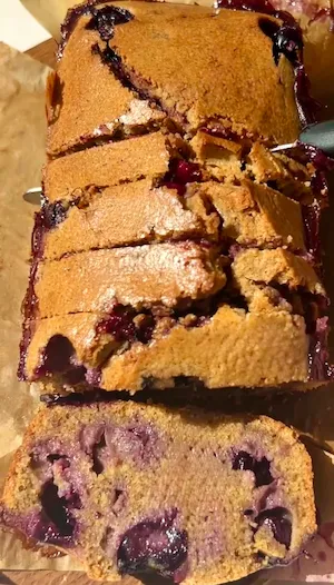 Mini blueberry olive oil loaf cake sliced on parchment paper showing the golden top and blueberry filled interior
