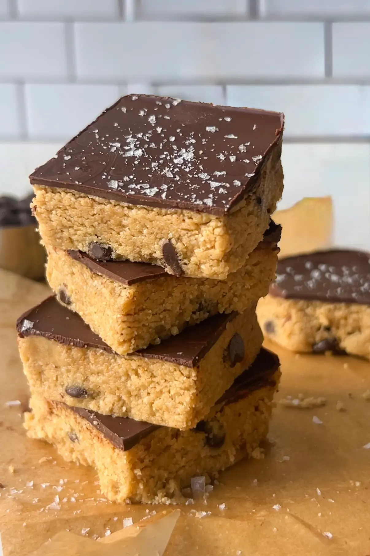 No bake cookie dough protein bars stacked with a thick dark chocolate topping and chocolate chips